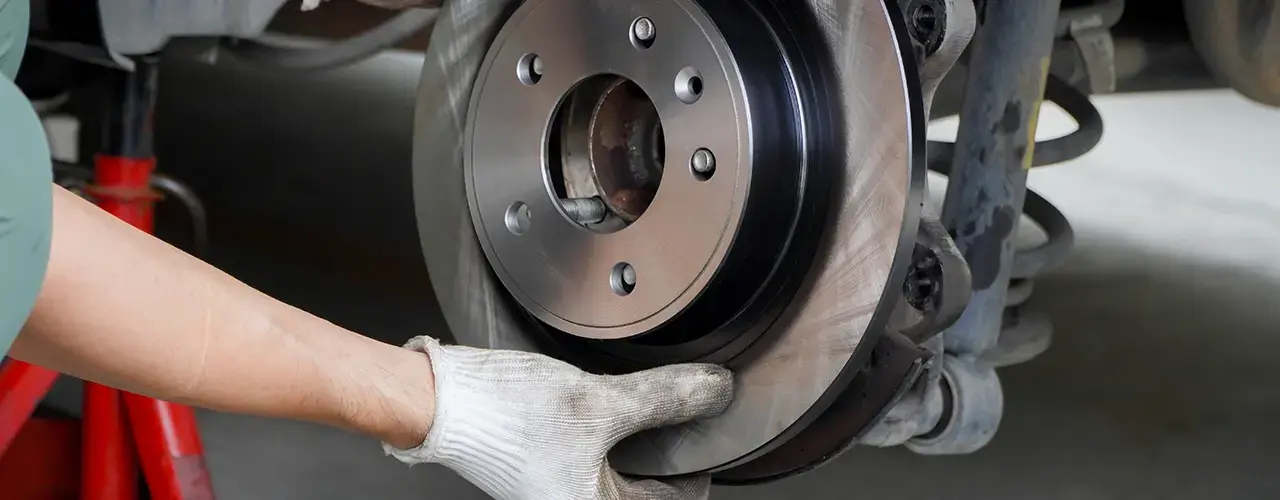 A person fitting a brake disc on a car